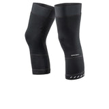 A pair of black knee warmers with a textured windbreaking fabric and reflective elements on the lower leg.