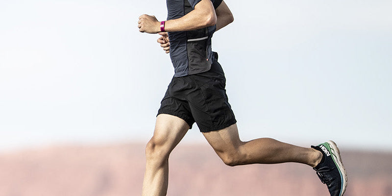Man running on a road with a desert landscape in the background